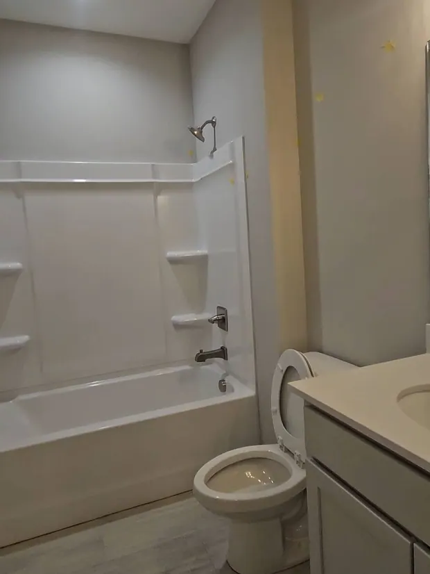 Bathroom before renovation with an existing tub surround, vanity, and toilet.