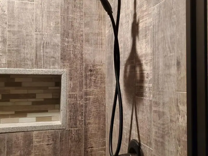 Shower lined in barnwood-look porcelain with a granite bench