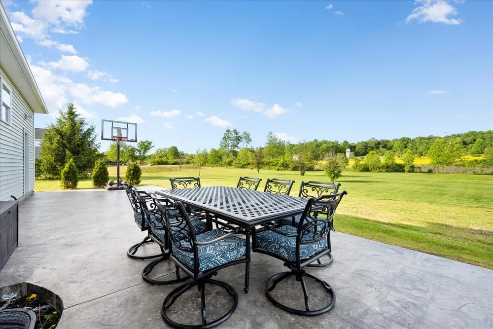 A stamped concrete patio with a dining set, looking out over open ground