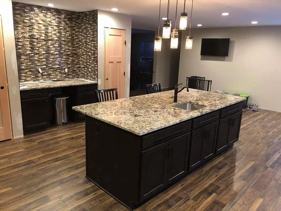 Granite island with dark cabinetry in the expanded kitchen in Central New York.