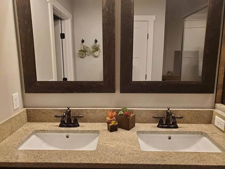 Double vanity with stone countertops and framed mirrors in Central New York.