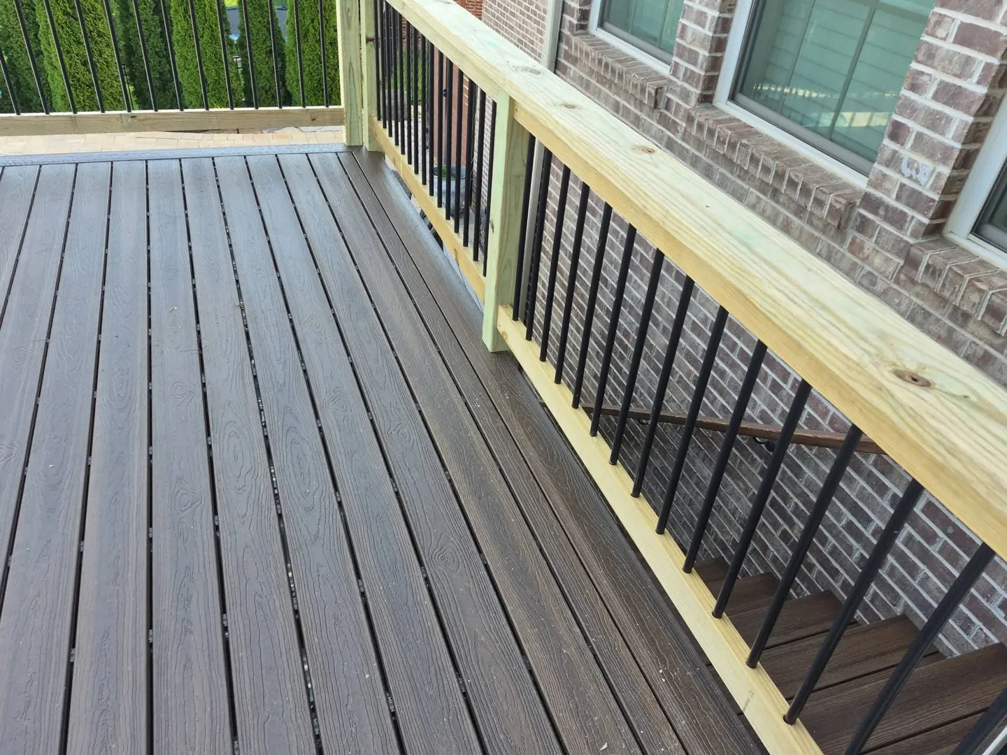 Composite deck boards beside a brick wall, with the railing and the stairs, in Farragut, TN.