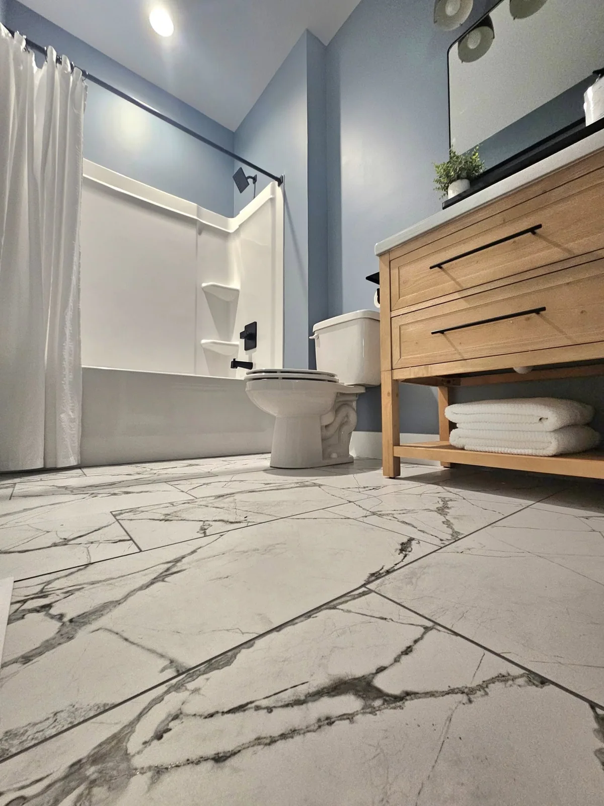Marble-look floor tile beside a freestanding wood vanity in Central New York.